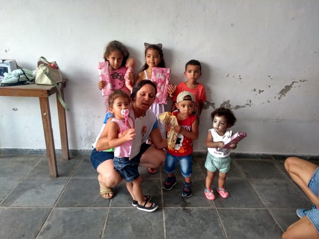 Educadora e crianças em ação de entrega de presentes